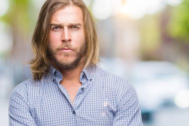 Yakışıklı delikanlı izole arka plan şüpheci ve sinir, onaylamayan ifade yüz çapraz kolları olan uzun saçlı. Negatif kişi.