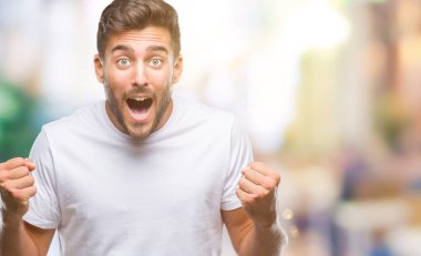 İzole arka plan kutlama üzerinde genç yakışıklı adam şaşırttı ve başarı için kaldırdı kollarını açarak hayret ve gözleri açık. Kazanan kavramı.