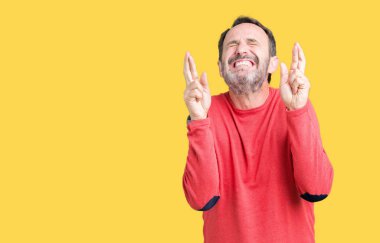 Umut ve gözleri kapalı geçiş parmaklarıyla gülümseyen izole arka plan üzerinde kış kazak giymiş yakışıklı orta yaş ağarmış komuta sizde. Şans ve batıl kavramı.