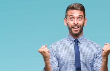 Genç yakışıklı iş adamı izole arka plan kutlama üzerinde şaşırttı ve başarı için kaldırdı kollarını açarak hayret ve gözleri açık. Kazanan kavramı.