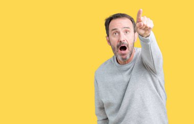 Yakışıklı orta yaş komuta sizde izole arka plan ile sürpriz devam et, parmakla üzerinde bir kazak giyen ağız açık ifade, önünde bir şey hayret