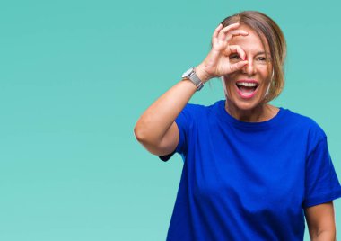 Orta yaş üst düzey İspanyol kadın gülümsüyor, parmakları ile mutlu yüz üzerinden seyir göz el ile ok jest yapıyor izole arka plan.