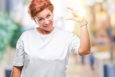 Atrractive üst düzey beyaz Kızıl saçlı kadın izole arka plan gülümseyen ve süre seyir ve kamera boyutu işaret parmaklarıyla yapıyor el ile kendine güvenen el hareketi yüzünden. Ölçü kavramı.