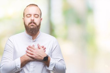 Göğüs kapalı gözler ve yüzünde minnettar jest ile izole arka plan ile gülümseyen üzerinde genç beyaz hispter adam eller. Sağlık kavramı.