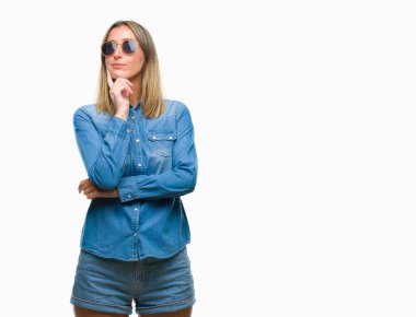 Genç güzel kadın elle çene düşünme hakkında soru, dalgın ifade izole arka plan üzerinde güneş gözlüğü takıyor. Düşünceli yüzüyle gülümsüyor. Şüphe kavramı.