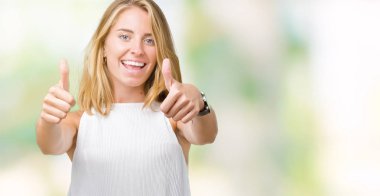 Güzel genç zarif kadın el ile pozitif jest yapıyor onaylama izole arka plan üzerinde başparmak gülümseyen ve başarı için mutlu. Kamera, kazanan jest arıyorsunuz.