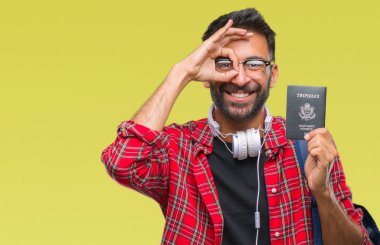 Amerika'nın yetişkin İspanyol öğrenci adam holding pasaport ile mutlu yüz el parmaklarının arasından seyir göz üzerinde ok işaretiyle yapıyor gülümseyen izole arka plan üzerinde