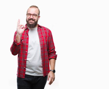 İzole arka plan el ve parmaklar ok işaretiyle yapıyor olumlu gülümseyen üzerinde gözlük takan Genç beyaz hipster adam. Başarılı ifade.