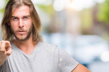 Yakışıklı delikanlı kamera ve size parmak ile işaret futbol topu tutan izole arka plan üzerinde uzun saçlı, el işareti, pozitif ve kendinden emin bir jest ön