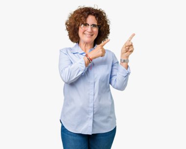 Gülümseyen ve iki elleri ve parmakları ile tarafına işaret kamera bakarak izole arka plan üzerinde gözlük güzel orta ager üst düzey businees kadın.