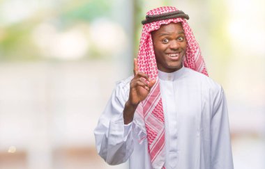 Başarılı fikirle izole arka plan işaret parmağı üzerinde geleneksel keffiyeh giyen genç Arapça Afrika adam. Çıktıktan ve mutlu. Bir numara.