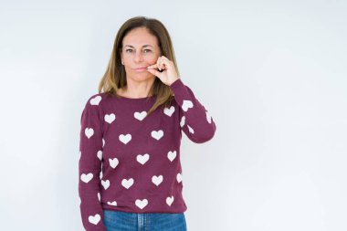 Arka plan ağız üzerinde kalp kazak giyen güzel orta yaş kadın izole ve parmak ile ZIP olarak Dudaklarını kapa. Gizli ve sessiz, tabu söz