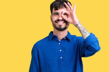 Genç yakışıklı adam gülümsüyor, parmakları ile mutlu yüz üzerinden seyir göz el ile ok jest yapıyor izole arka plan üzerinde.