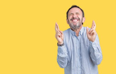 Yakışıklı orta yaş geçiş parmakları umut ve gözleri kapalı ile gülümseyen izole arka plan üzerinde zarif komuta sizde. Şans ve batıl kavramı.