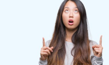 Genç Asyalı kadın izole arka plan üzerinden hayran ve yukarıya bakıp parmakları ile işaret şaşırttı ve silah kaldırdı.