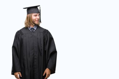 Genç yakışıklı adam uzun saçlı görünümlü yan ve dik dik bakma uzağa düşünce gülümseyen izole arka plan üzerinde mezun..