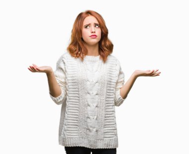 İzole arka plan kış kazak clueless ve şaşkın bir ifadeyle kollar ve eller kaldırdı giyen genç güzel kadın. Şüphe kavramı.