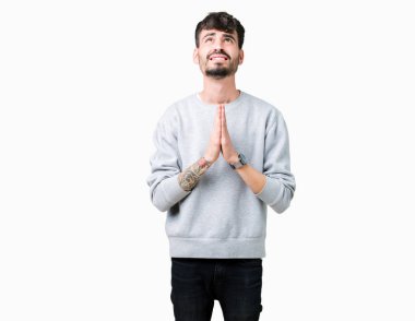 Yalvarıyor ve umut ifade yüzünde çok duygusal ve endişe ile birlikte elleriyle dua izole arka plan üzerinde kazak giyen genç yakışıklı adam. Bağışlanmak. Din kavramı.