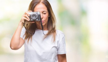 Orta yaş İspanyol kadın vintage fotoğraf makinesi ile acımak yüz ciddi düşünüyorum üstünde kendine güvenen bir ifade izole arka plan üzerinde kullanarak fotoğraf çekme