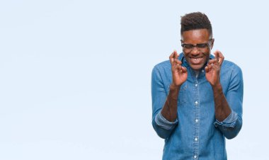 Afrikalı-Amerikalı genç umut ve gözleri kapalı geçiş parmaklarıyla gülümseyen izole arka plan üzerinde. Şans ve batıl kavramı.