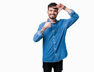 Yakışıklı delikanlı elle yapma çerçeve ve parmakları ile mutlu yüz gülümseyen izole arka plan üzerinde. Yaratıcılık ve Fotoğrafçılık kavramı.