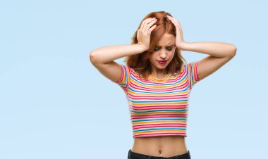 Genç ve güzel bir kadın, izole edilmiş arka planda acı ve migren yüzünden çaresiz ve stresli bir baş ağrısı çekiyor. Ellerini başının üstüne koy..