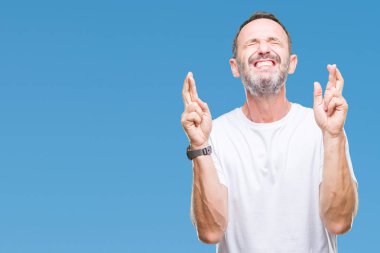 Umut ve gözleri kapalı geçiş parmaklarıyla gülümseyen izole arka plan üzerinde beyaz t-shirt giyen orta yaş ağarmış komuta sizde. Şans ve batıl kavramı.