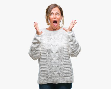 Üzerinde kış kazak giyen orta yaş üst düzey İspanyol kadın deli kutluyor arka plan izole ve başarı için kaldırdı kollarını açarak hayrete ve heyecanlı çığlık gözleri açık. Kazanan kavramı