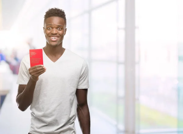 立っていると自信を持って歯を見せて笑顔で笑っている幸せそうな顔でスイス連邦共和国のパスポートを保持して若いアフリカ系アメリカ人 — ストック写真
