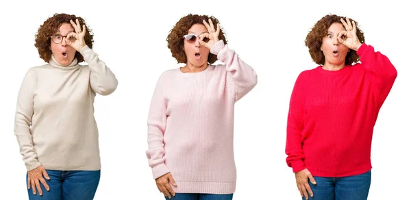 中年老年妇女穿着冬季毛衣在白色孤立的背景做确定的手势震惊与惊讶的脸 眼睛通过手指看 不相信的表达 — 图库照片
