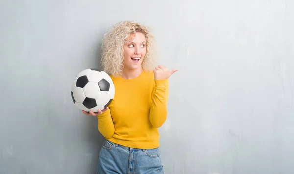 Junge Blonde Frau Über Grunge Grauem Hintergrund Den Fußballball Zeigend — Stockfoto