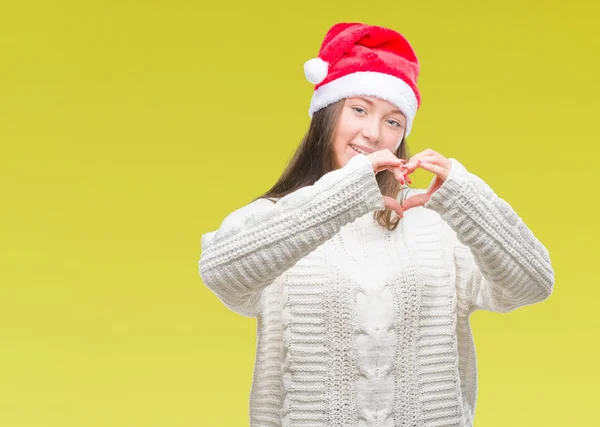 若い美しい白人女性のハートマークと手で形を示す愛の笑みを浮かべて隔離された背景にクリスマス帽子をかぶっています ロマンチックな概念 — ストック写真