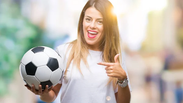 若くてきれいな女性の手と指で指している非常に満足の孤立した背景にサッカー ボールを保持しています — ストック写真