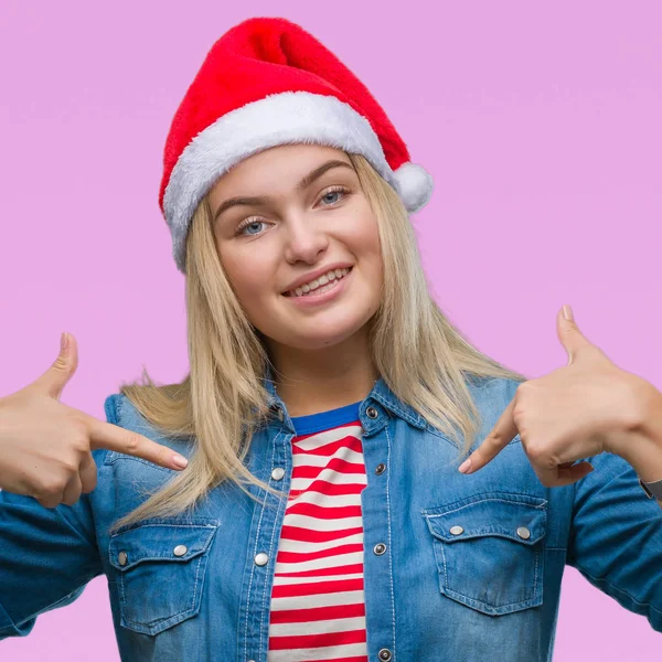 若い白人女性の顔に笑顔と自信を持って 誇りと幸せな指で自分を指している孤立した背景にクリスマスの帽子をかぶって — ストック写真