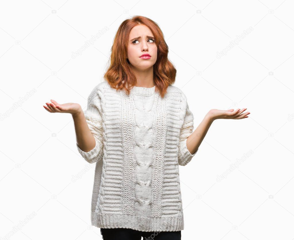Young beautiful woman over isolated background wearing winter sweater clueless and confused expression with arms and hands raised. Doubt concept.