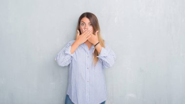 Gri grunge duvar eller için hata ile ağız kapsayan şok moda iş kıyafeti giymiş genç yetişkin kadın. Gizli kavramı.