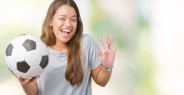 Genç güzel esmer kadın futbol futbol topu tutan kocaman bir gülümseme ile çığlık zaferini kutluyor ve ellerini kaldırdı arka plan çok mutlu ve heyecanlı, kazanan ifade izole