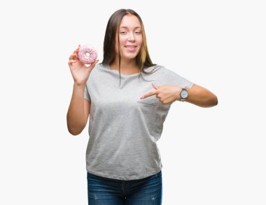 Sürpriz yüz işaret parmağı kendini izole arka plan üzerinde tatlı çörek yiyen genç kafkas kadın