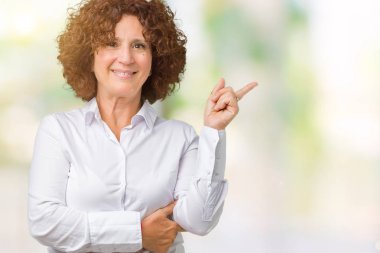 Yüzünde kocaman bir gülümseme ile izole arka plan güzel orta ager üst düzey businees kadın kameraya bakarak yan el ve parmak ile işaret.