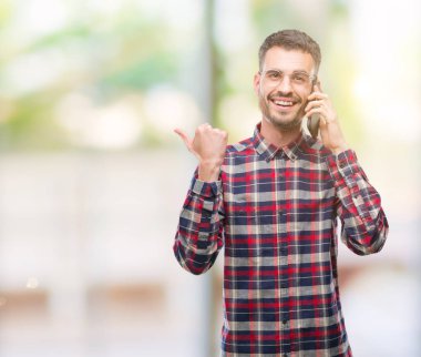 İşaret ve başparmak kadar mutlu yüz gülümseyen tarafı ile gösterilen telefonda konuşan genç yenilikçi yetişkin adam