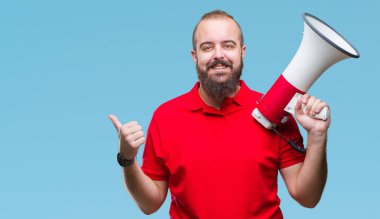 Beyaz delikanlı işaret ve başparmak kadar mutlu yüz gülümseyen tarafı ile gösteren izole arka plan üzerinde megafon ile bağırarak