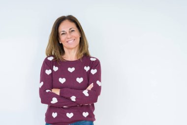 Üzerinde kalp kazak giyen güzel orta yaş kadın mutlu yüz ile gülümseyerek kameraya seyir silah geçti arka plan izole. Olumlu bir kişi.