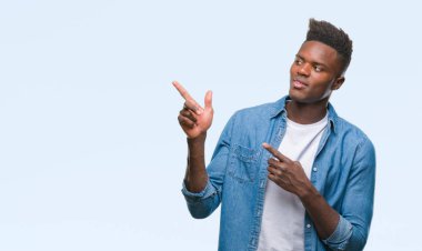 Gülümseyen ve iki elleri ve parmakları ile tarafına işaret kamera bakarak izole arka plan üzerinde genç Afro-Amerikan adam.