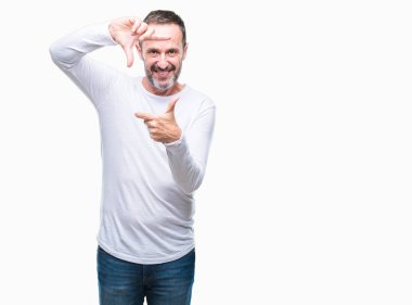 Elle yapma çerçeve ve parmakları ile mutlu yüz gülümseyen izole arka plan üzerinde beyaz t-shirt giyen orta yaş ağarmış komuta sizde. Yaratıcılık ve Fotoğrafçılık kavramı.