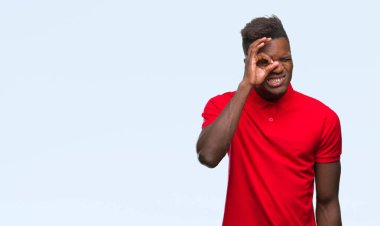 Genç Afro-Amerikan adam gülümsüyor, parmakları ile mutlu yüz üzerinden seyir göz el ile ok jest yapıyor izole arka plan üzerinde.