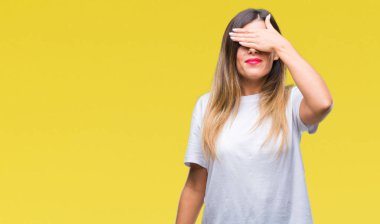 Casual beyaz t-shirt üzerine gülümsüyor ve gözleri için sürpriz kapsayan yüz el ile gülüyor arka plan izole genç güzel kadın. Kör kavramı.