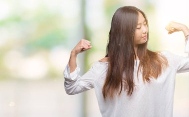 Genç Asyalı kadın kol kasları gururlu gülümseyen gösterilen izole arka plan üzerinde. Fitness kavramı.