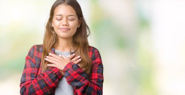 İle gülümseyen izole arka plan üzerinde bir ceket giyen genç güzel esmer kadın kapalı gözler ve yüzünde minnettar jest ile göğüs üzerinde eller. Sağlık kavramı.