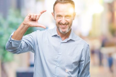 Orta yaş ağarmış üst düzey iş adamı izole arka plan gülümseyen ve boyutu işaret parmaklı ararken ve kamera işi el ile kendinden emin eller üzerinde. Ölçü kavramı.