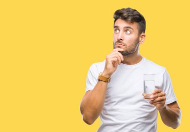 Yakışıklı delikanlı izole arka plan ciddi bir yüz düşünme hakkında soru, çok karışık bir fikir üzerinde bardak su içme